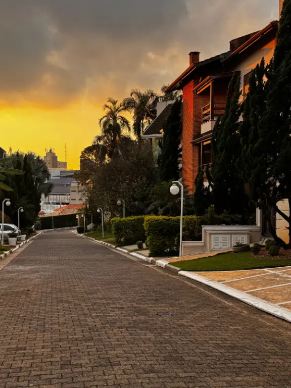 Rua interna arborizada do condomínio, ao entardecer